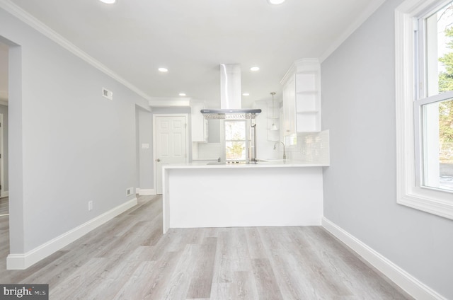 kitchen with white cabinetry, kitchen peninsula, island range hood, and decorative backsplash