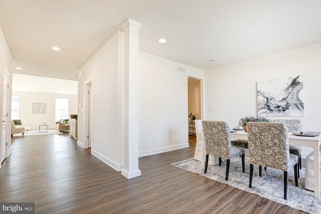 dining space featuring dark wood-type flooring and ornate columns