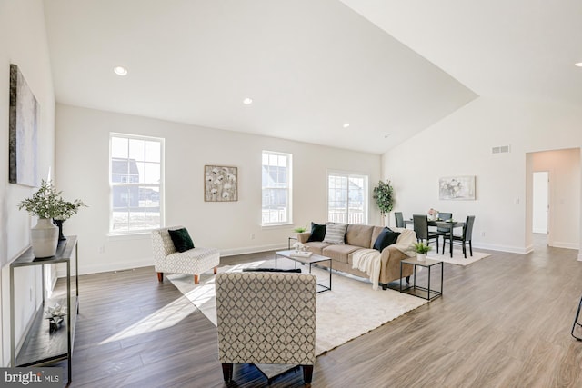 living room featuring vaulted ceiling, a healthy amount of sunlight, and dark hardwood / wood-style floors