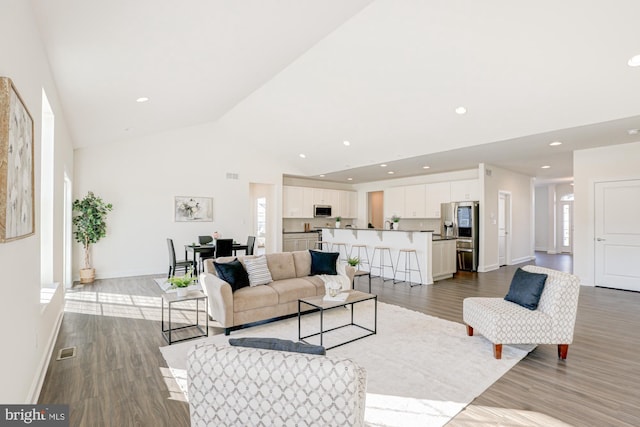 living room with light hardwood / wood-style floors, vaulted ceiling, and a wealth of natural light