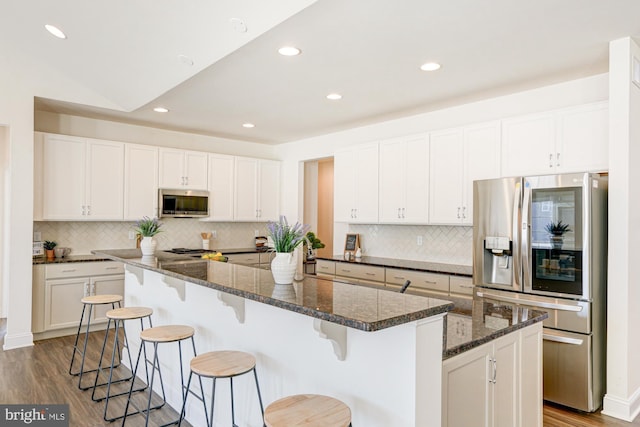 kitchen with stainless steel appliances, white cabinetry, a center island, and wood-type flooring