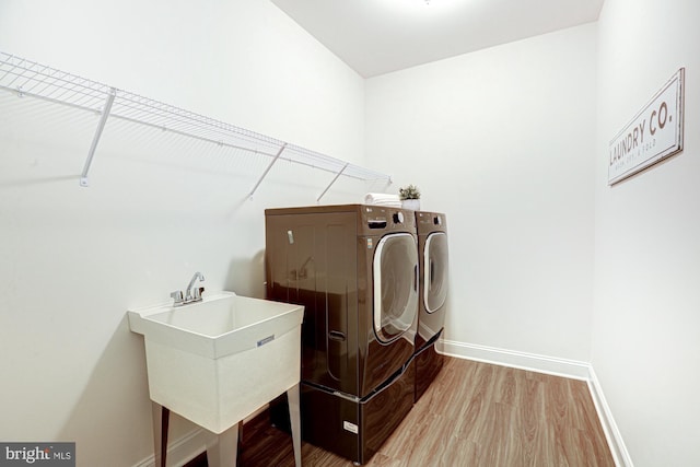 laundry room featuring sink, washing machine and dryer, and wood-type flooring