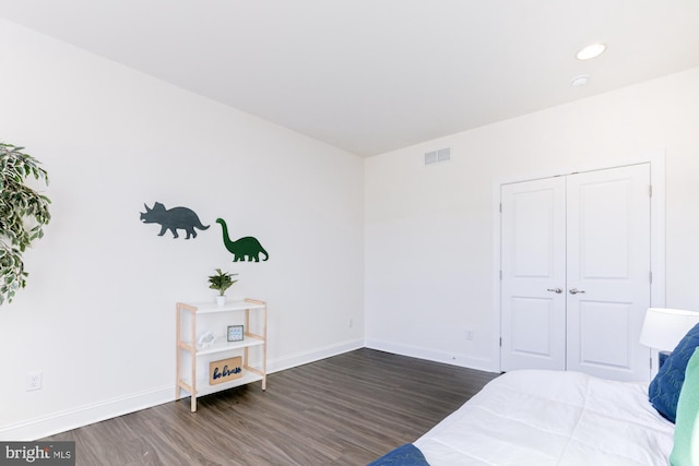 bedroom with dark hardwood / wood-style flooring and a closet