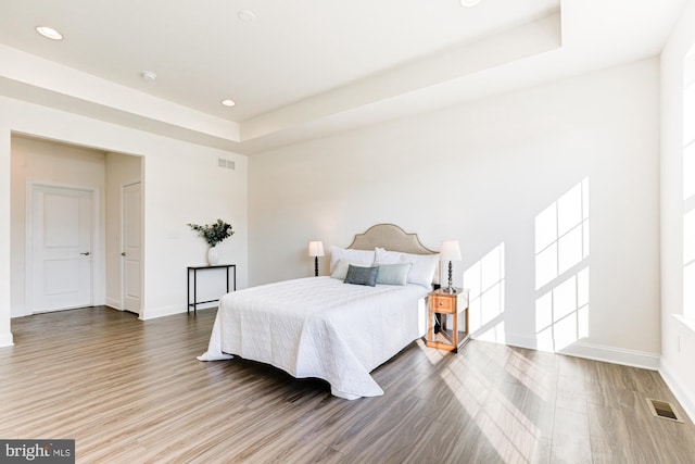 bedroom with hardwood / wood-style floors and a tray ceiling