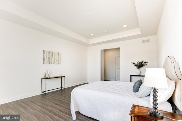 bedroom with a tray ceiling and dark hardwood / wood-style floors