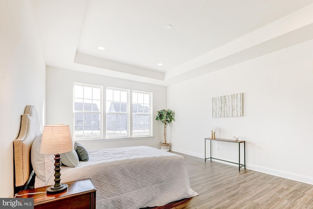 bedroom with hardwood / wood-style flooring and a tray ceiling