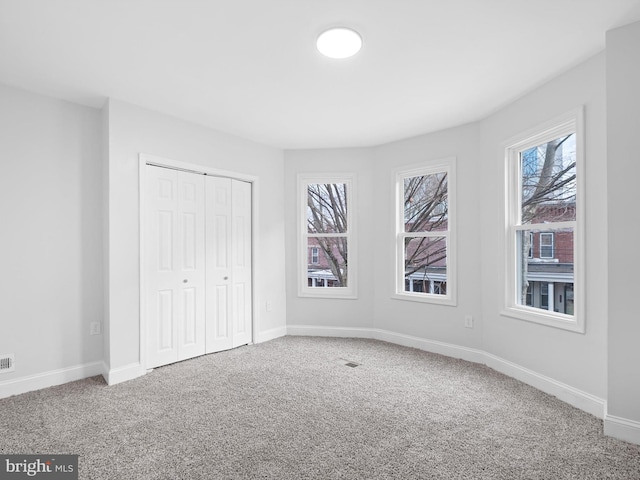 unfurnished bedroom with carpet, a closet, and multiple windows