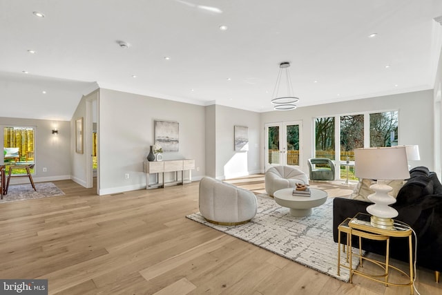 living room featuring crown molding, light hardwood / wood-style floors, and french doors