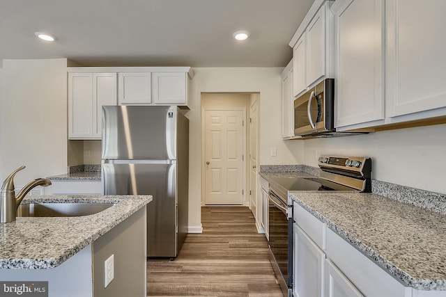 kitchen with white cabinets, sink, light hardwood / wood-style flooring, appliances with stainless steel finishes, and light stone counters