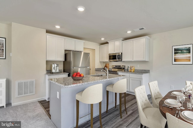 kitchen with light stone counters, sink, white cabinetry, and stainless steel appliances