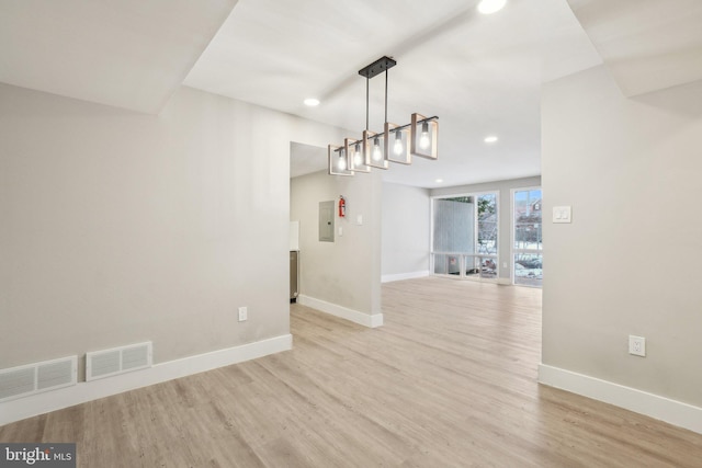 unfurnished dining area featuring electric panel and light hardwood / wood-style floors