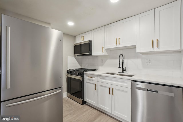 kitchen with sink, stainless steel appliances, white cabinets, and backsplash