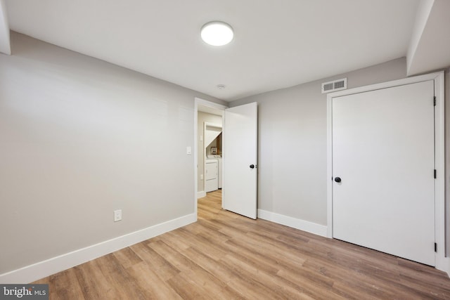 unfurnished bedroom featuring light hardwood / wood-style floors, a closet, and washer / clothes dryer