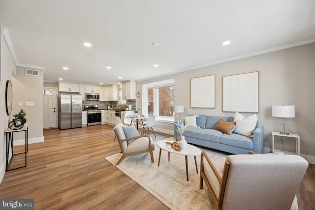 living room with crown molding and light hardwood / wood-style floors