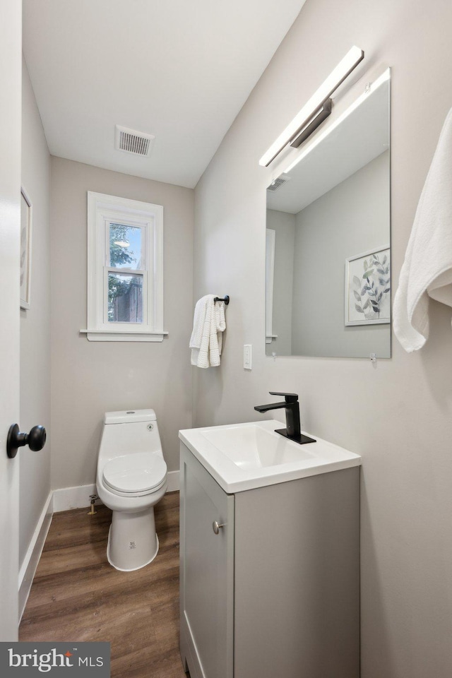 bathroom with vanity, toilet, and hardwood / wood-style floors