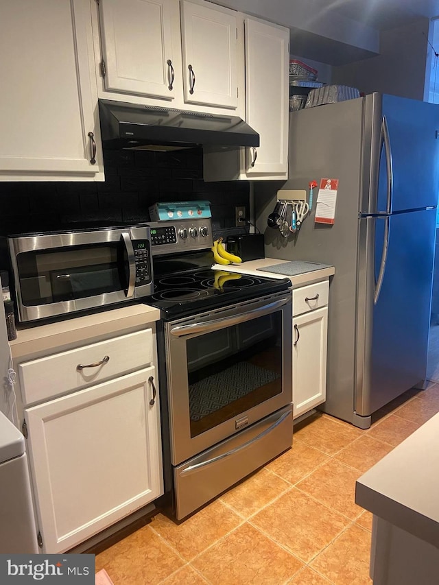 kitchen featuring white cabinetry, stainless steel appliances, light tile patterned floors, and tasteful backsplash