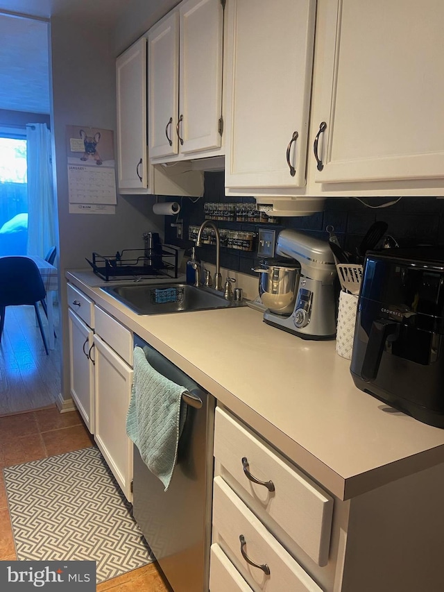 kitchen featuring white cabinets, dishwasher, sink, and light tile patterned floors