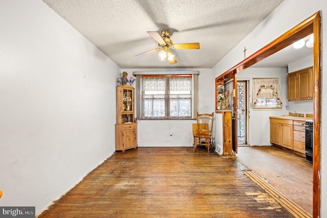 unfurnished dining area featuring dark hardwood / wood-style flooring, a textured ceiling, and ceiling fan