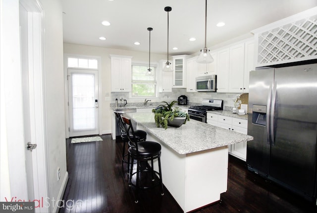 kitchen with decorative light fixtures, white cabinets, appliances with stainless steel finishes, and a center island