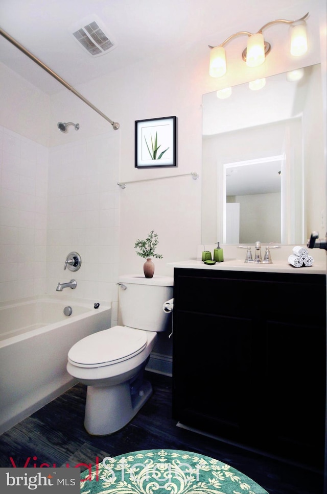 full bathroom with toilet, wood-type flooring, vanity, and tiled shower / bath combo