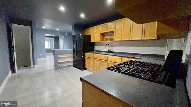 kitchen with black refrigerator, sink, light brown cabinets, and a baseboard heating unit