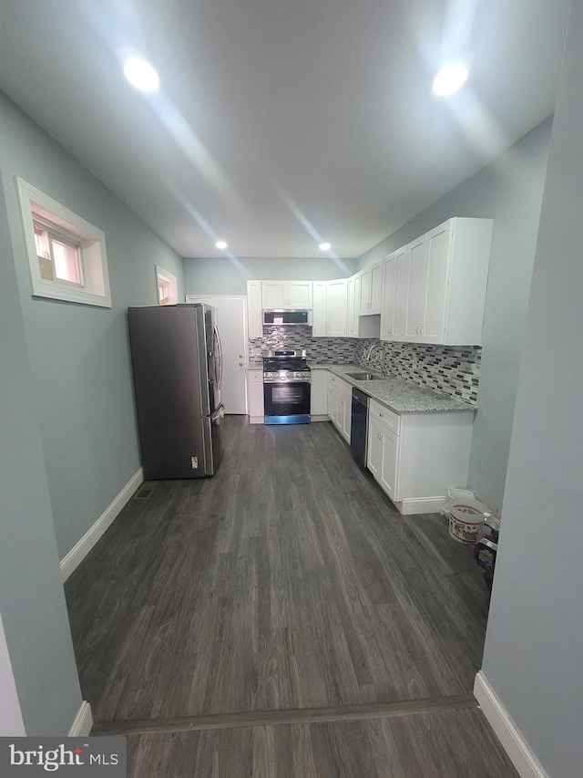 kitchen with light stone countertops, stainless steel appliances, extractor fan, dark wood-type flooring, and white cabinetry