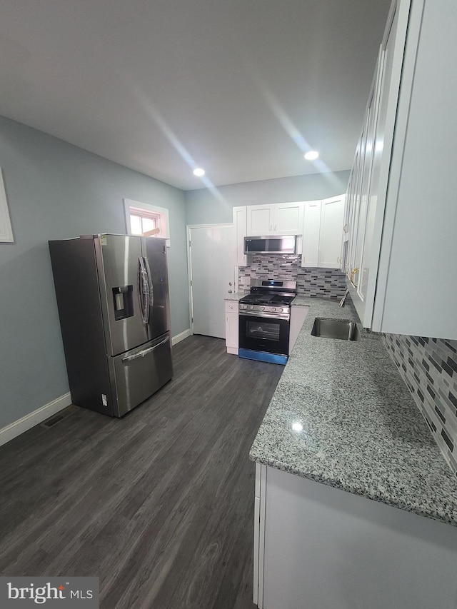 kitchen with white cabinetry, light stone countertops, tasteful backsplash, dark hardwood / wood-style floors, and appliances with stainless steel finishes