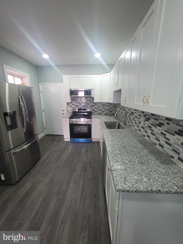 kitchen featuring white cabinets, sink, light stone countertops, dark hardwood / wood-style flooring, and stainless steel appliances