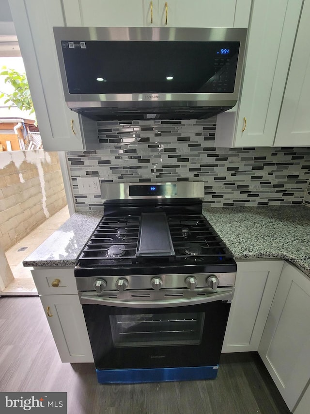 kitchen featuring backsplash, light stone countertops, white cabinetry, and stainless steel appliances