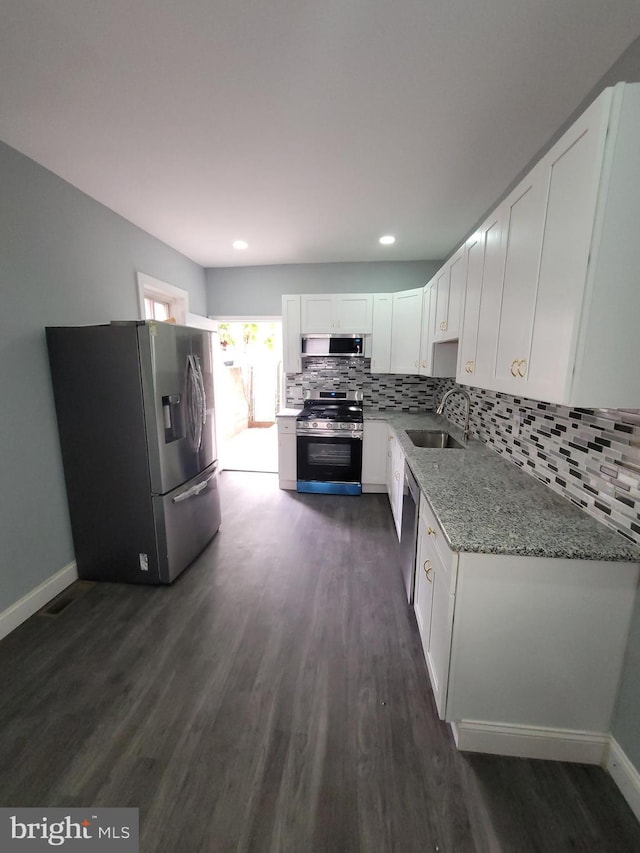 kitchen with white cabinetry, sink, light stone countertops, dark hardwood / wood-style flooring, and appliances with stainless steel finishes