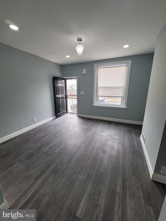 unfurnished room featuring dark hardwood / wood-style flooring and a notable chandelier