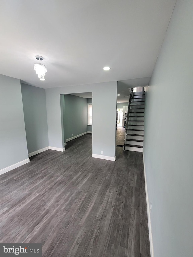 basement featuring dark wood-type flooring and an inviting chandelier