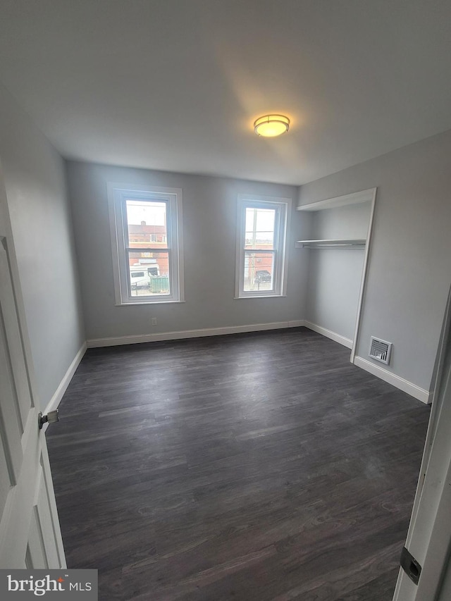 unfurnished bedroom with dark hardwood / wood-style flooring and a closet