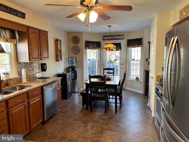 kitchen with stainless steel appliances, light stone countertops, ceiling fan, decorative backsplash, and sink