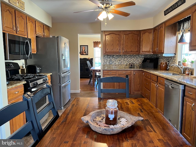 kitchen featuring sink, stainless steel appliances, dark hardwood / wood-style floors, and light stone countertops