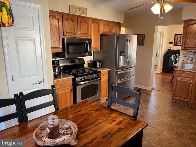 kitchen with light stone countertops, appliances with stainless steel finishes, ceiling fan, and backsplash