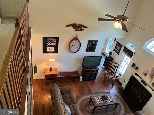 living room with a high ceiling, ceiling fan, and dark hardwood / wood-style floors