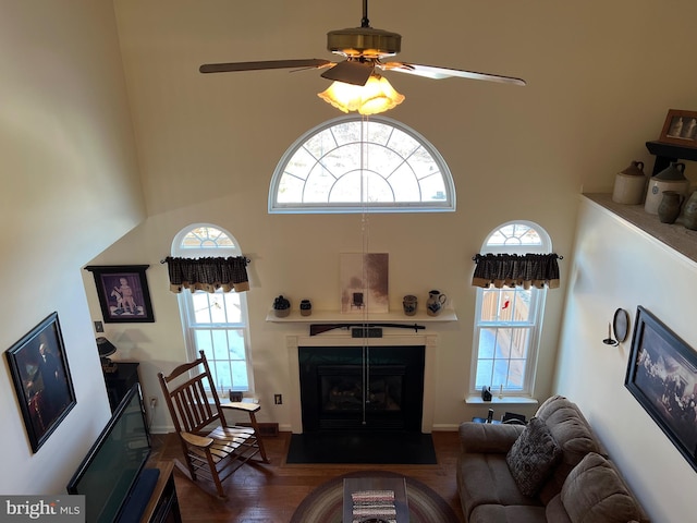 living room featuring a towering ceiling, ceiling fan, and dark hardwood / wood-style flooring