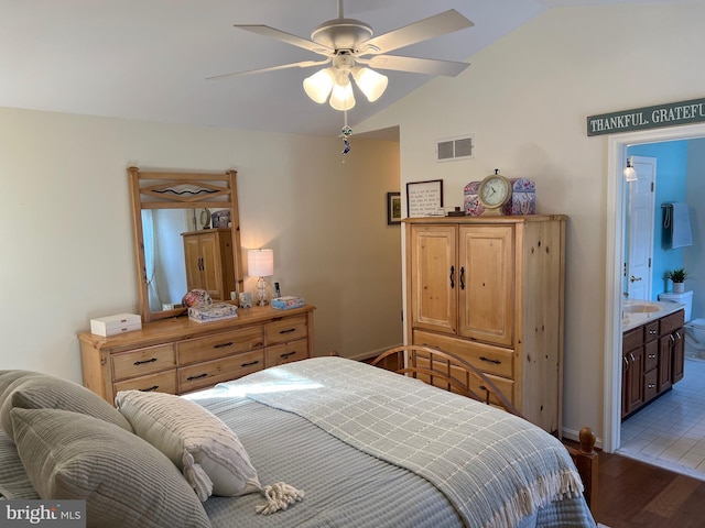 bedroom featuring ceiling fan, light hardwood / wood-style floors, ensuite bathroom, and vaulted ceiling