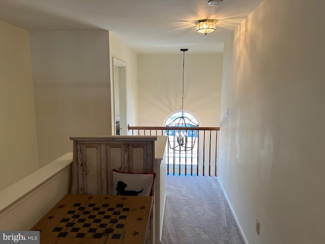 hallway featuring a notable chandelier and carpet flooring