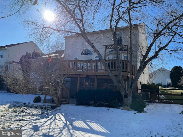 snow covered house featuring a wooden deck