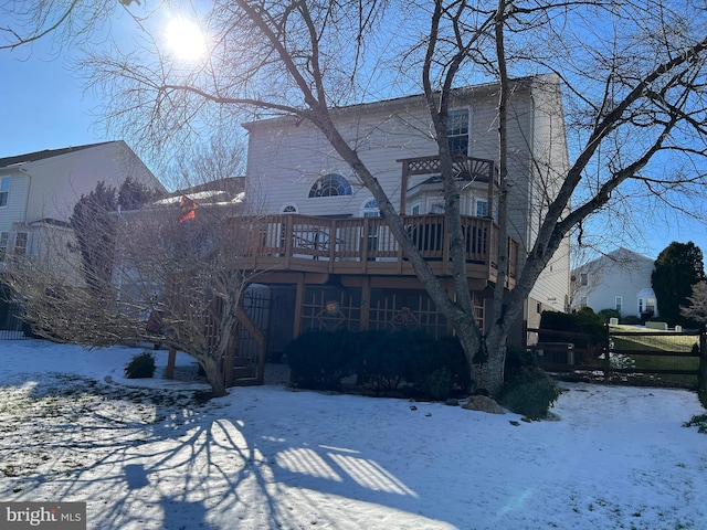 snow covered house featuring a wooden deck