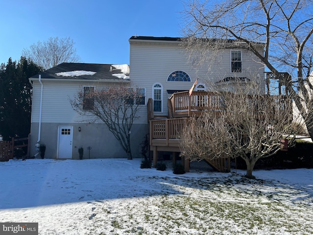 snow covered back of property with a deck