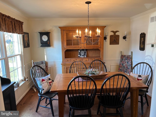 dining space with dark hardwood / wood-style flooring, ornamental molding, and a notable chandelier