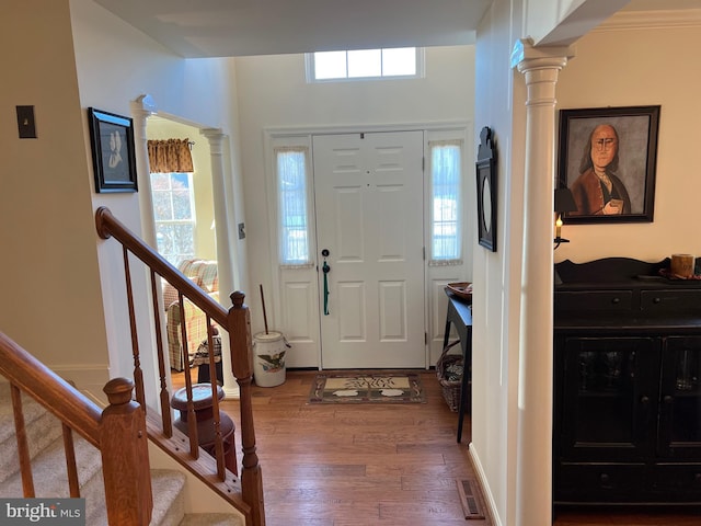 foyer entrance featuring ornate columns and dark wood-type flooring