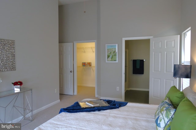 bedroom featuring a spacious closet, a closet, a towering ceiling, and carpet flooring