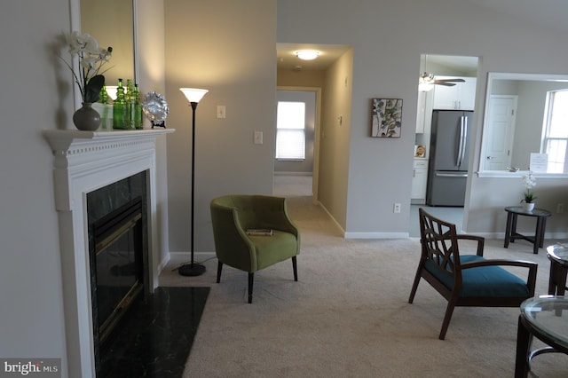 living room with ceiling fan, light carpet, and a fireplace