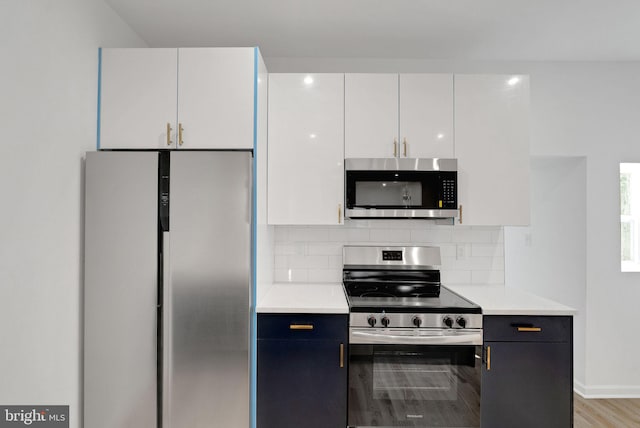 kitchen featuring white cabinets, light wood-type flooring, tasteful backsplash, and appliances with stainless steel finishes