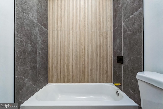 bathroom featuring toilet and tiled shower / bath