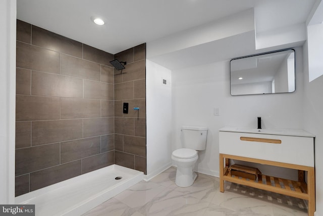 bathroom with tiled shower, vanity, and toilet